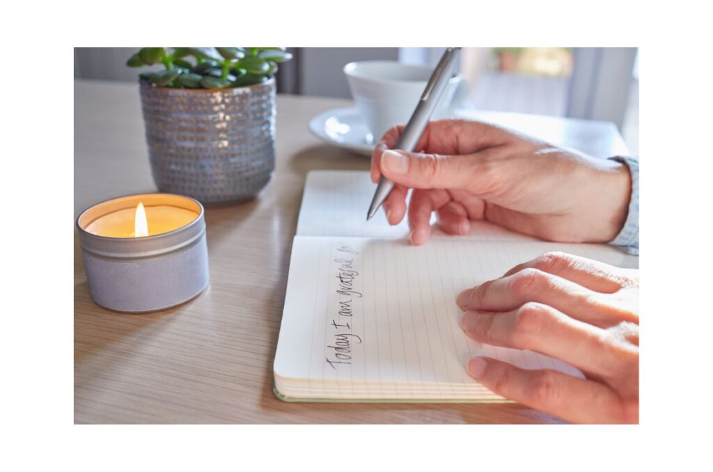 Hands writing in a gratitude journal.
