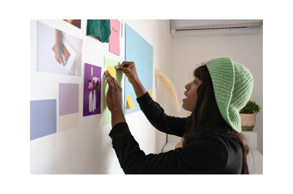 Woman pinning pictures up on a vision board.