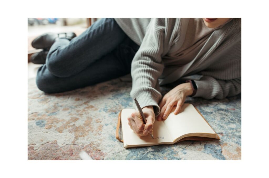 Woman writing in her journal on the floor.